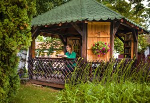 A woman is holding a book while standing inside of a gazebo filled with books on the walls.