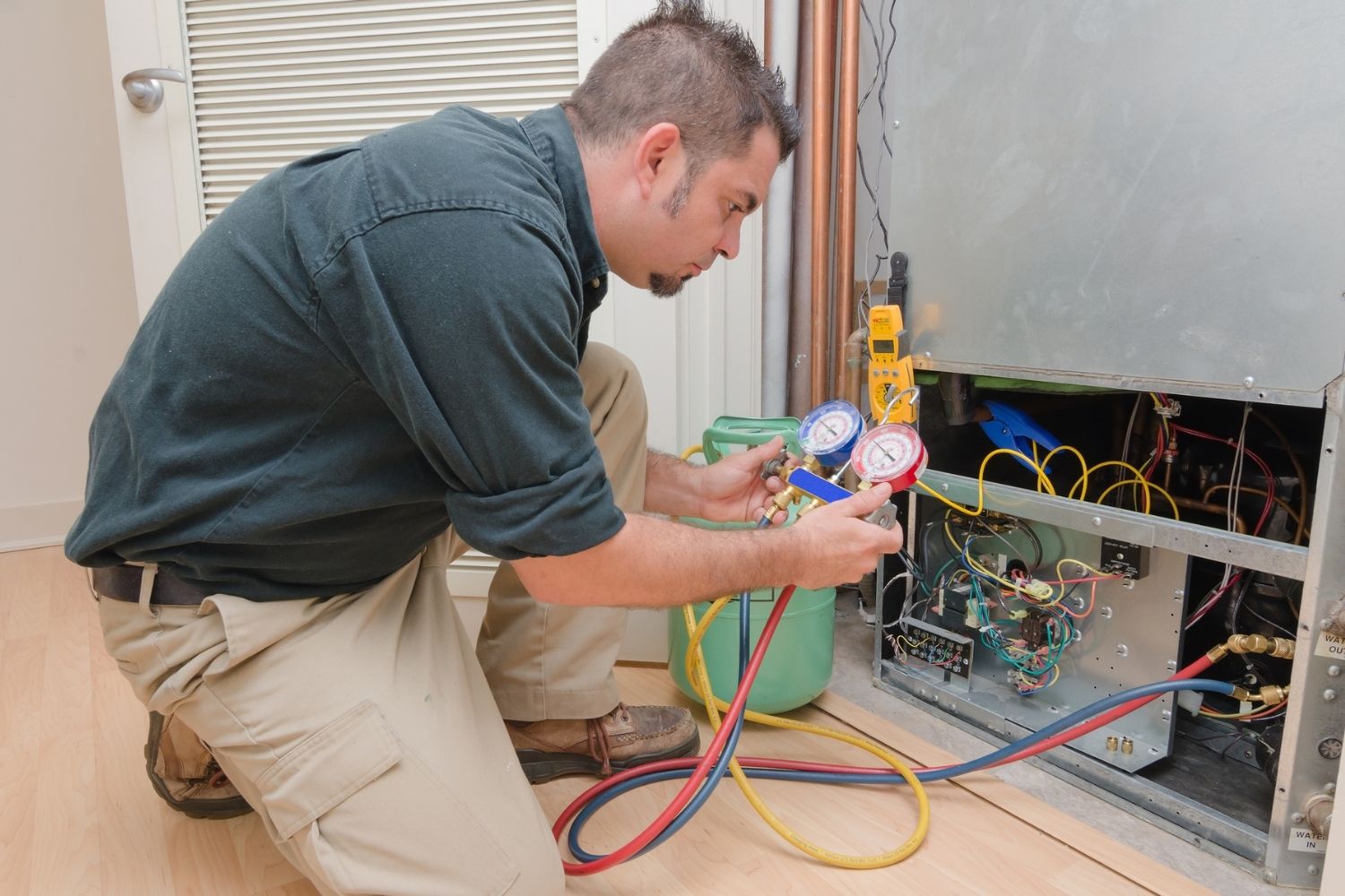 A worker uses a tool to test the functioning of an HVAC unit.