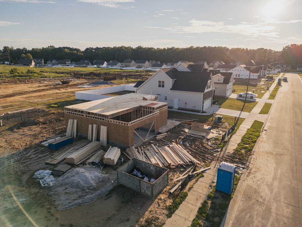 A home is undergoing construction next to several completed homes in a neighborhood.