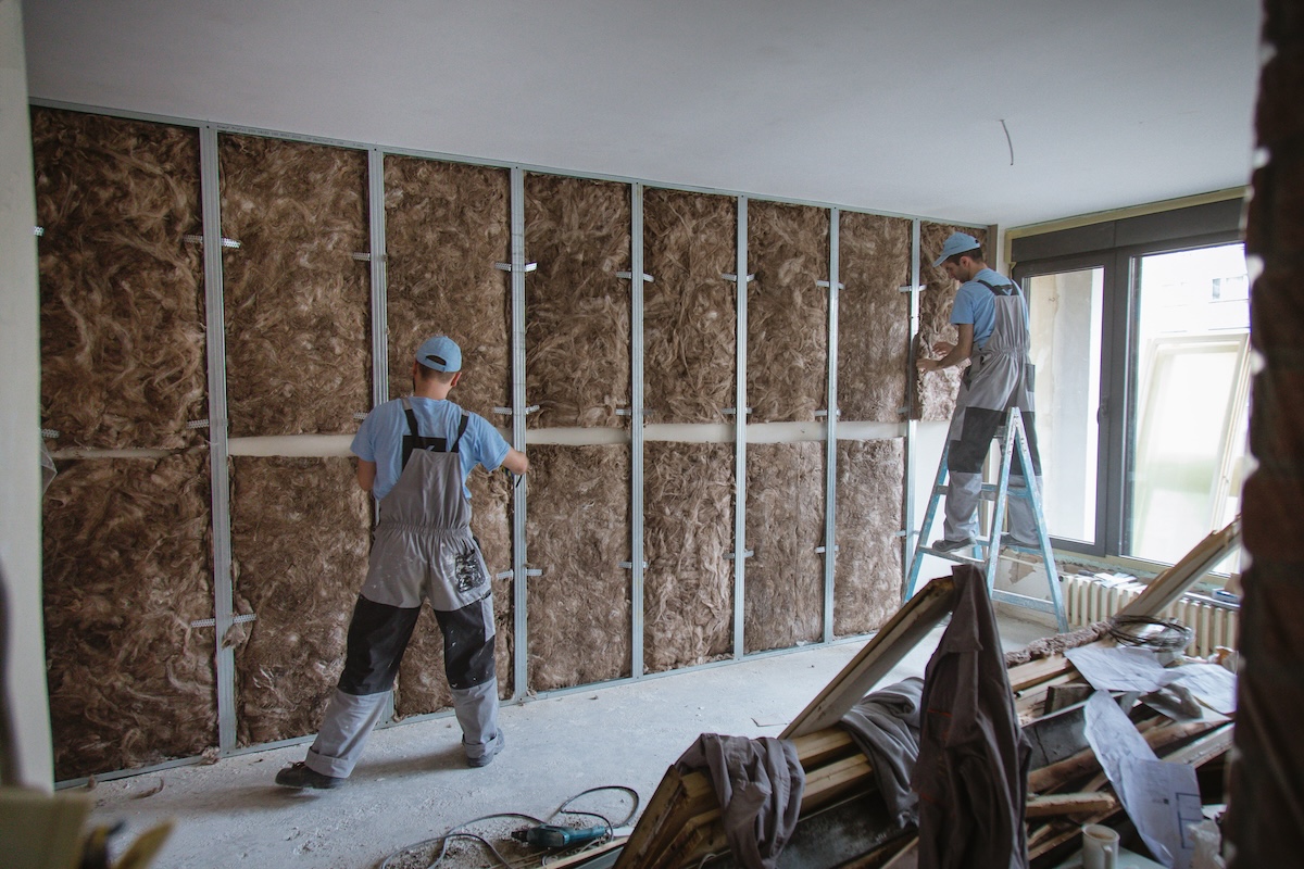 Construction workers install faced insulation.