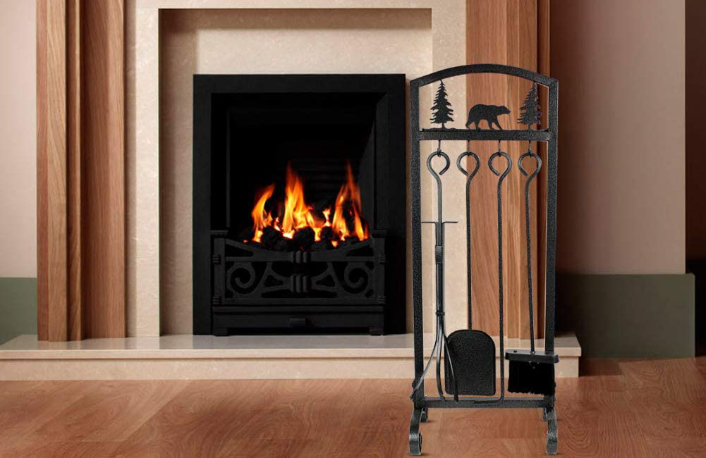 A set of the best fireplace tools on a wood floor next to a built-in fire place.