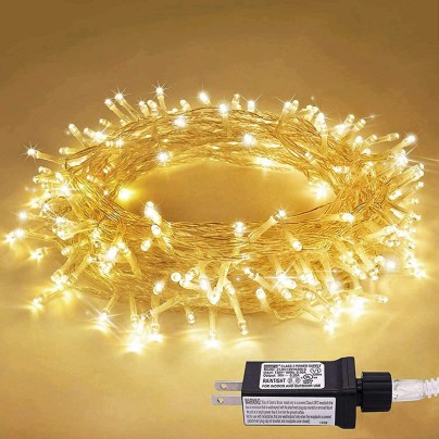 The JMEXSUSS 33-Foot 100 LED Indoor String Lights wound in a circle and set on a counter providing a warm yellow glow.