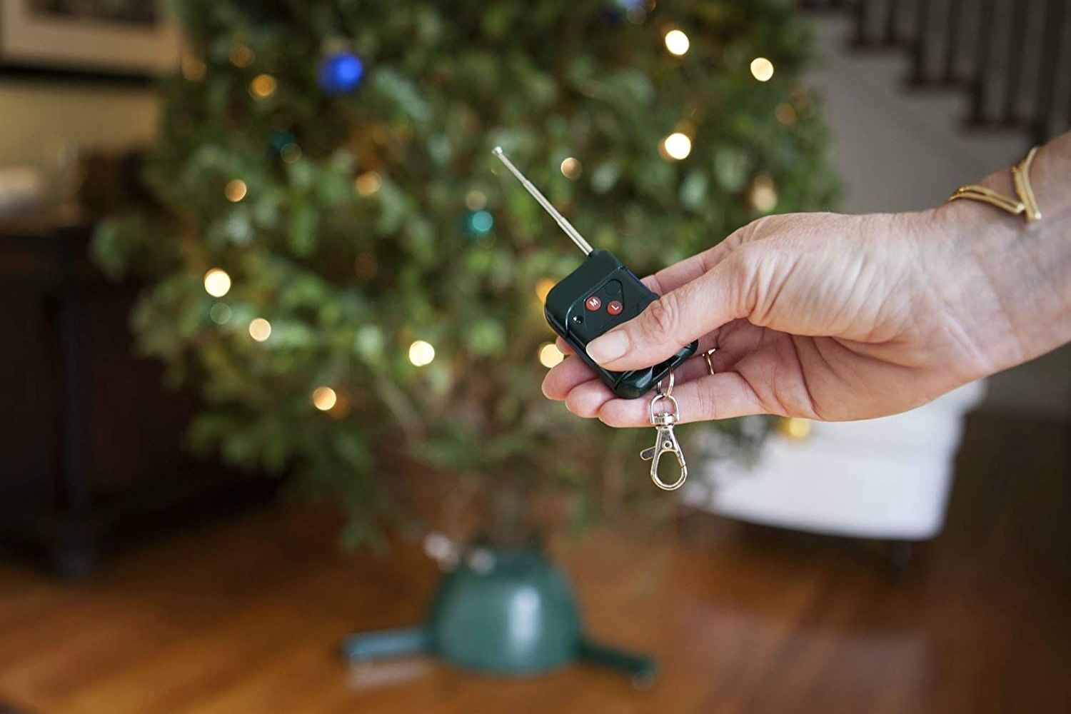 A person using a small remote to adjust the settings on the best rotating Christmas tree stand