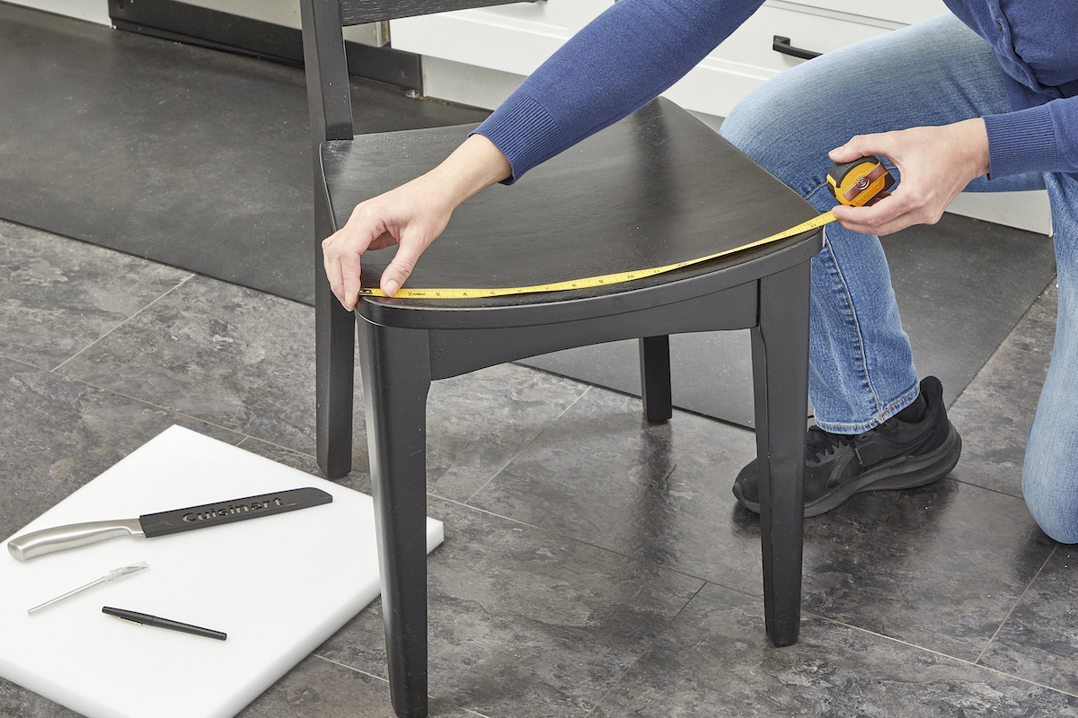 Woman using a tape measure to measure the seat on a chair.
