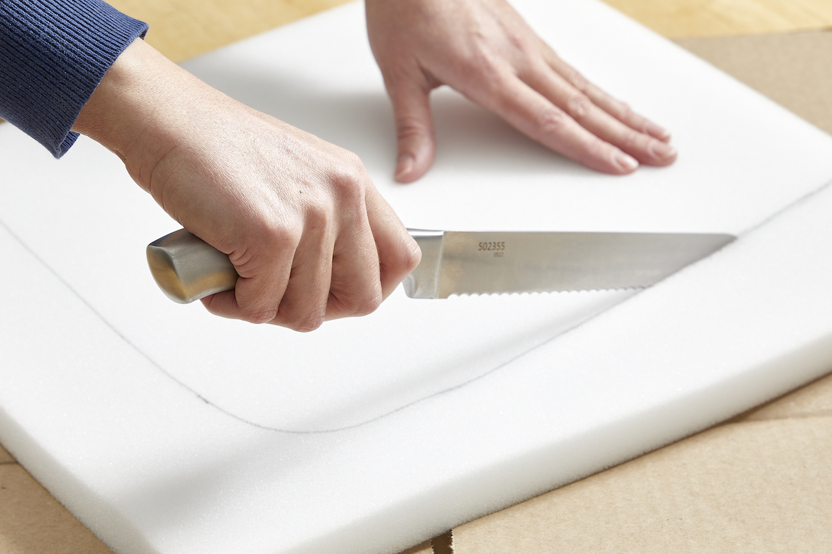 Woman cutting foam with a serrated knife.