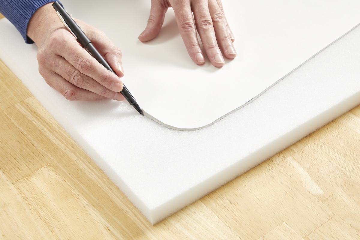 Woman tracing a poster board template onto a piece of foam.