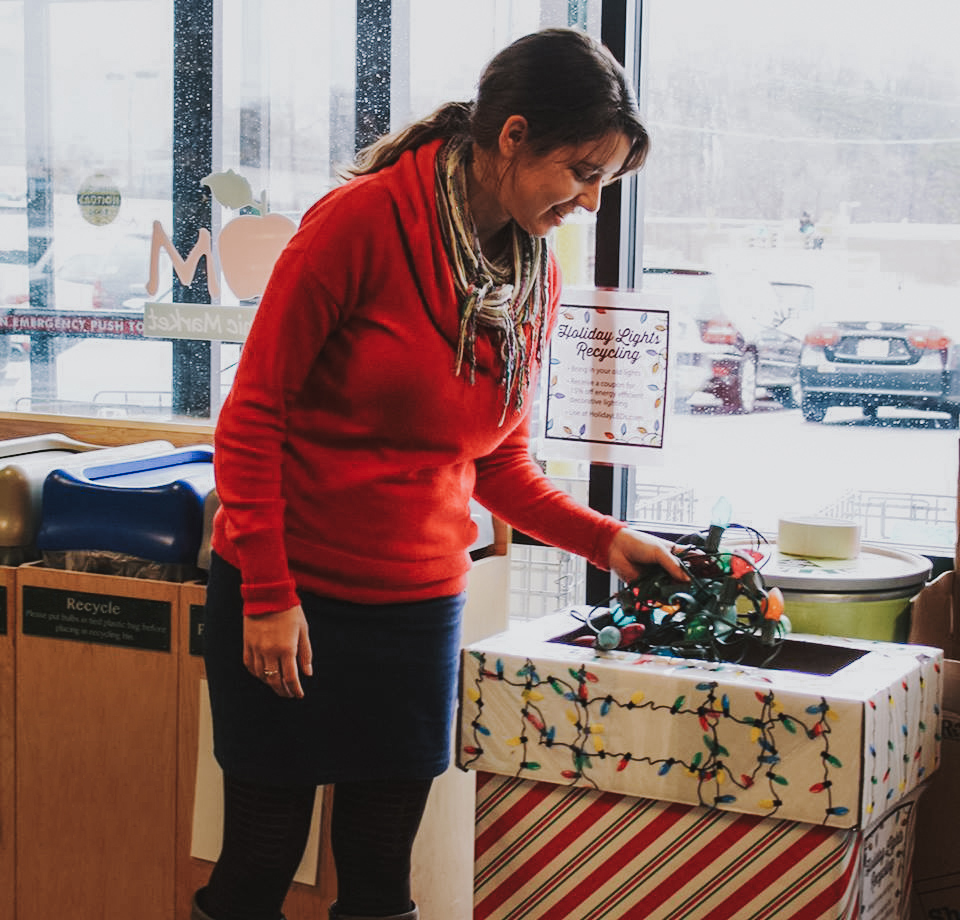 Woman recycling Christmas lights at Mom's Organic Market