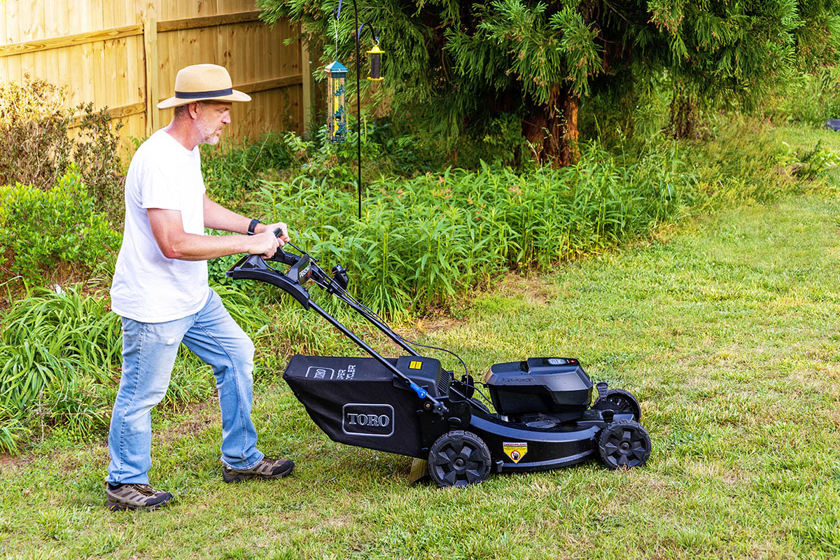 A man pushing the best lawn mower while mowing his yard