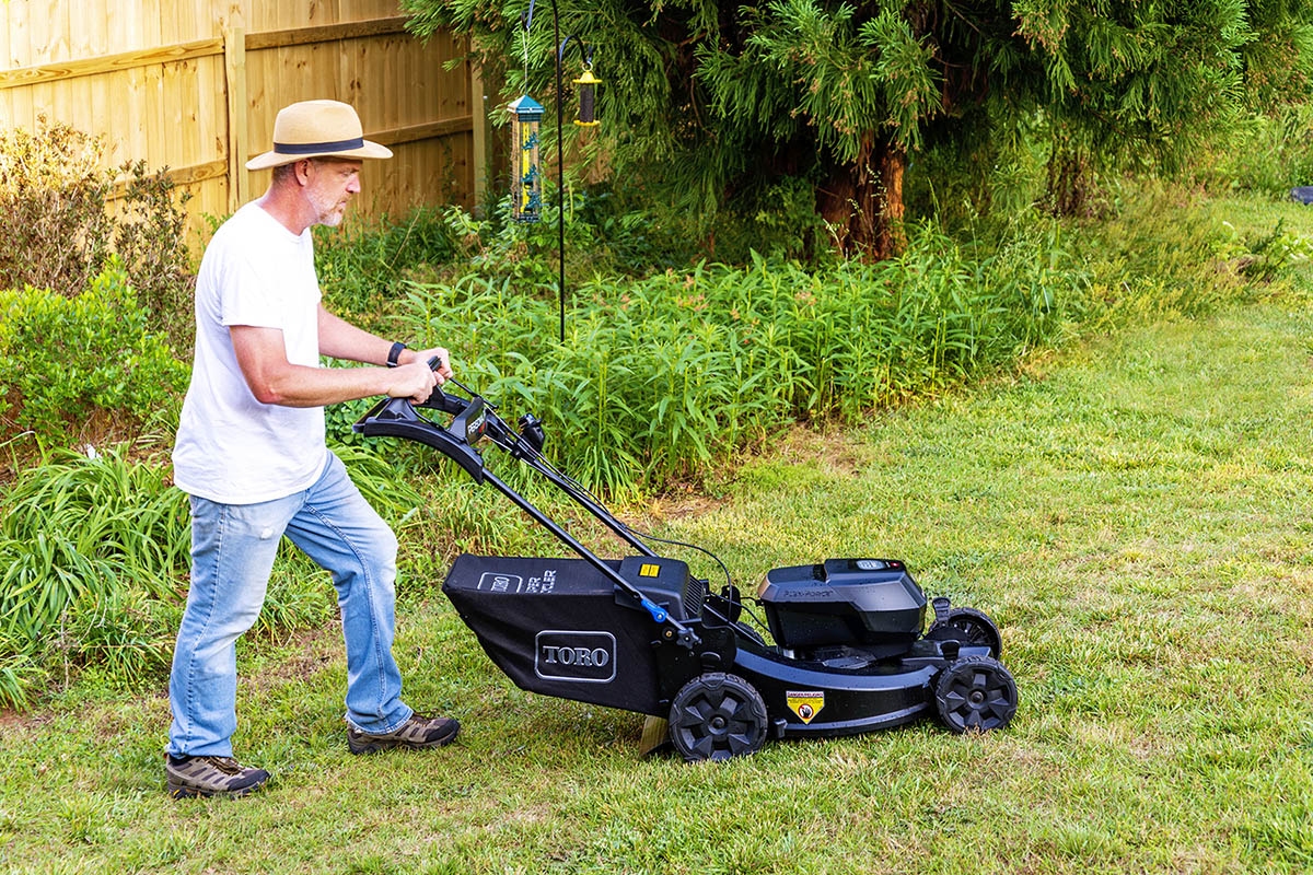 A man pushing the best lawn mower while mowing his yard