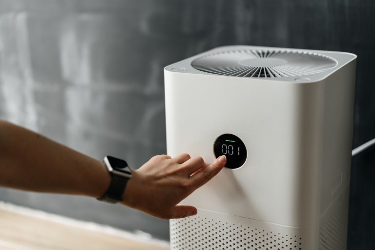Woman's hand presses the touch screen button to start an air purifier.
