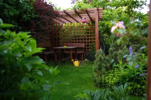 A wooden gazebo tucked away in a tropical backyard garden.