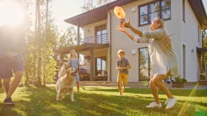 A family playing Frisbee on the lawn with their dog.