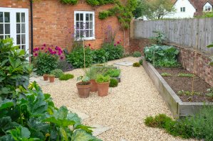 A backyard with a raised garden and gravel used for landscaping instead of grass.