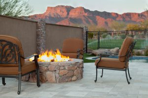 A large stone fire pit next to partial privacy fence.