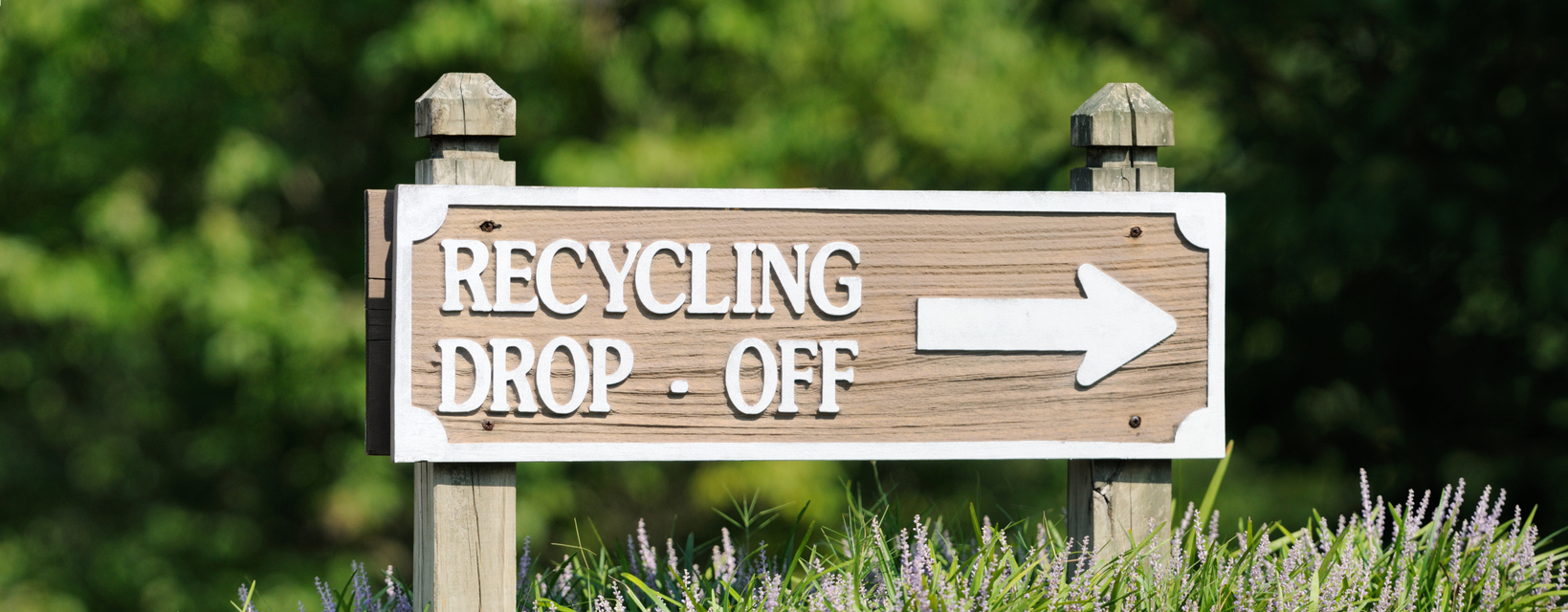 Wood sign with arrow that says "recycling drop off."