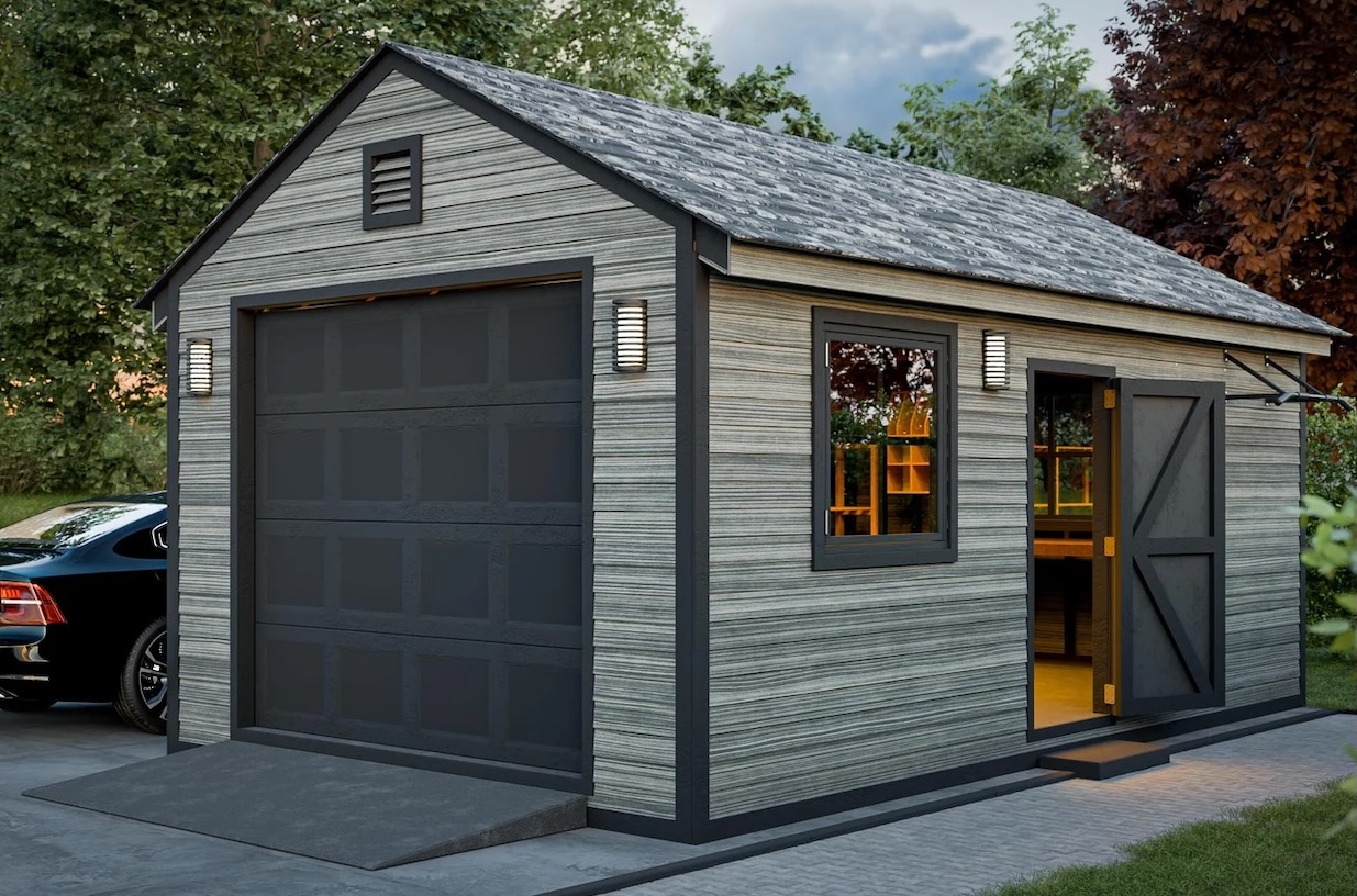 Grey detached garage with black garage door with black car parked outside.