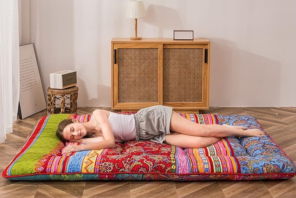 Woman sleeping on MAXYOYO roll-out Japanese mattress futon in Bohemian pattern.