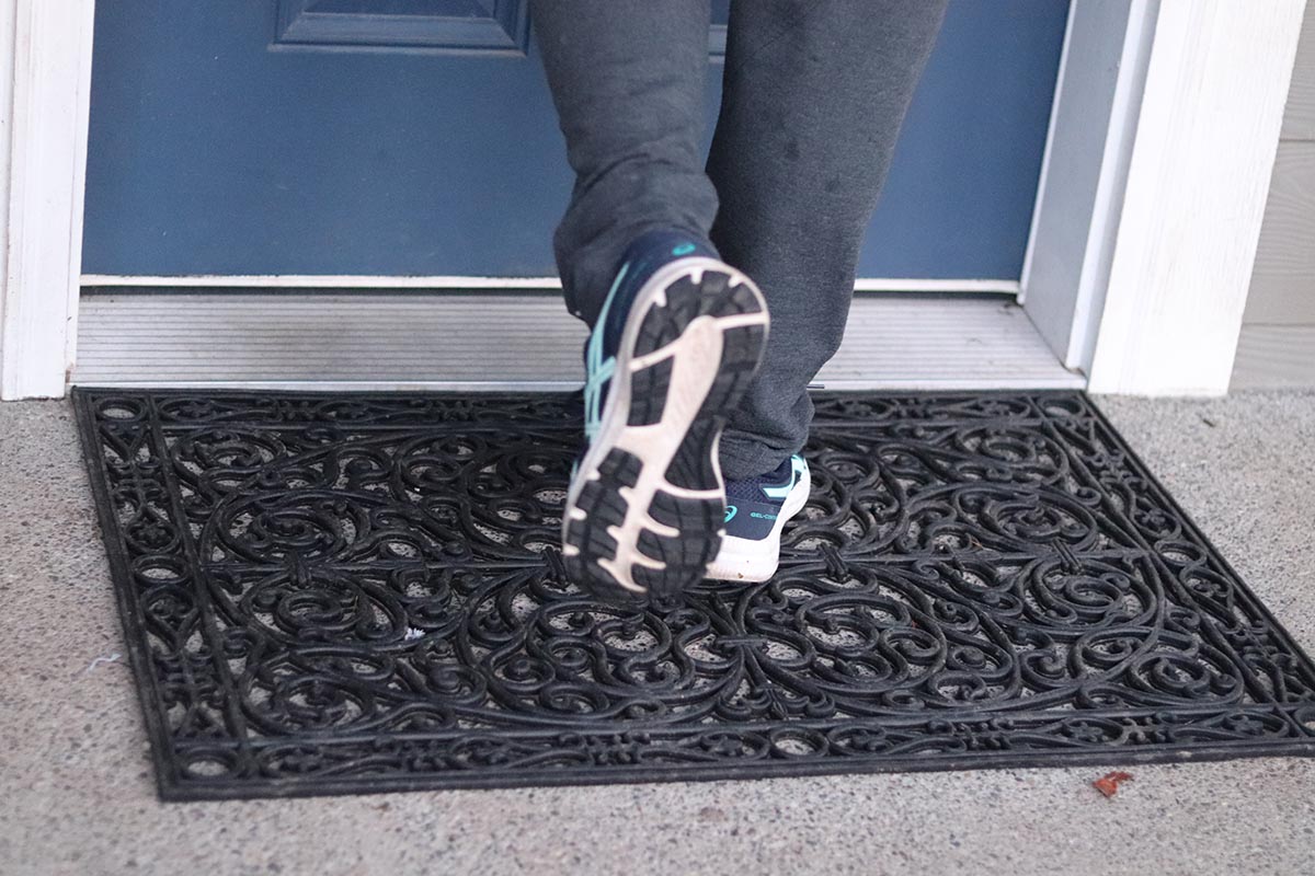 Person wiping their tennis shoes on decorative rubber doormat