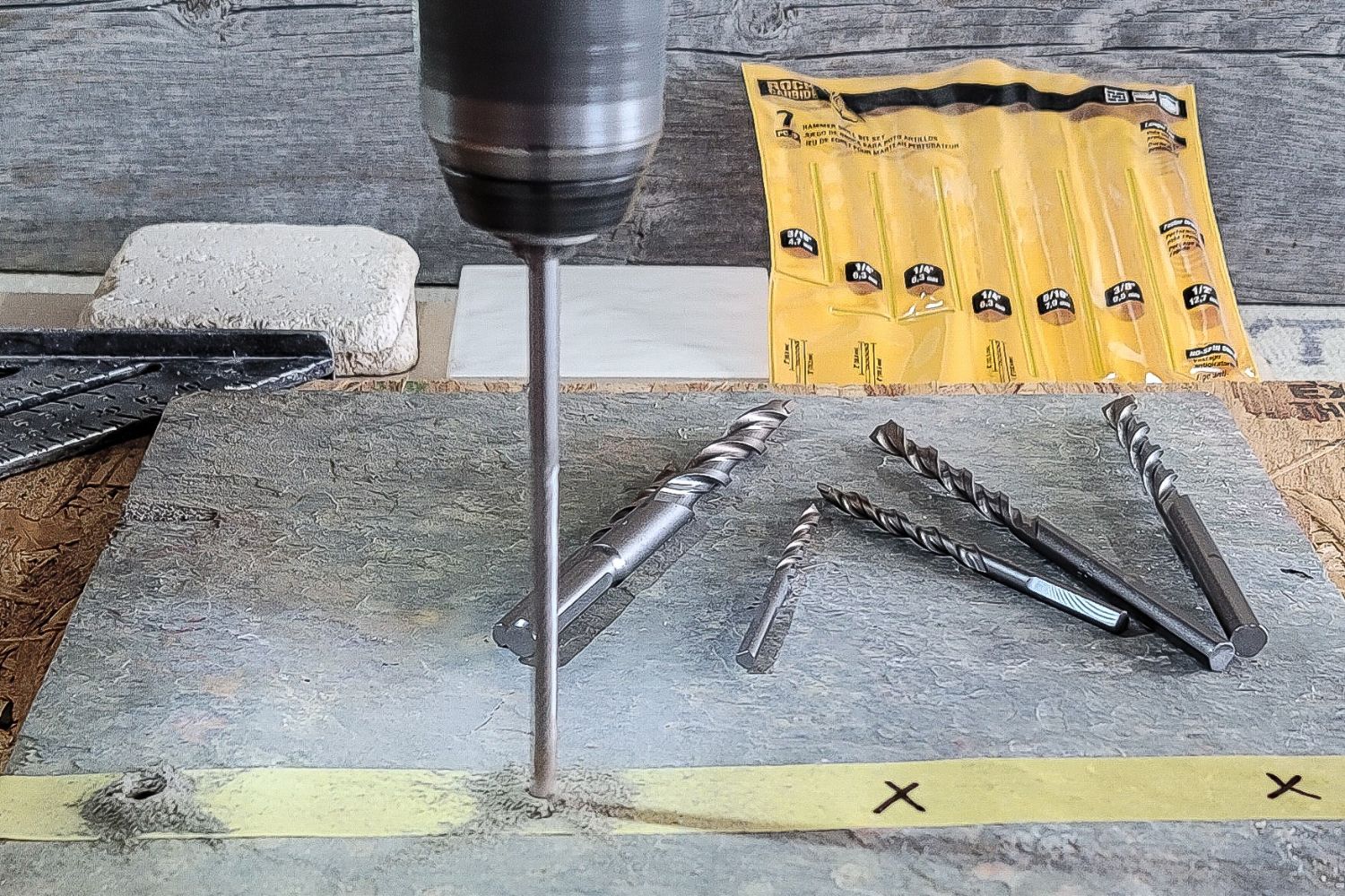 Long drill bit boring into large-scale gray tile