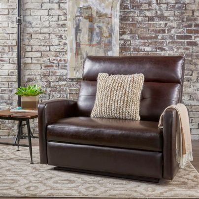 The Christopher Knight Home Halima Leather Recliner on a tan and white rug in front of a brick wall.