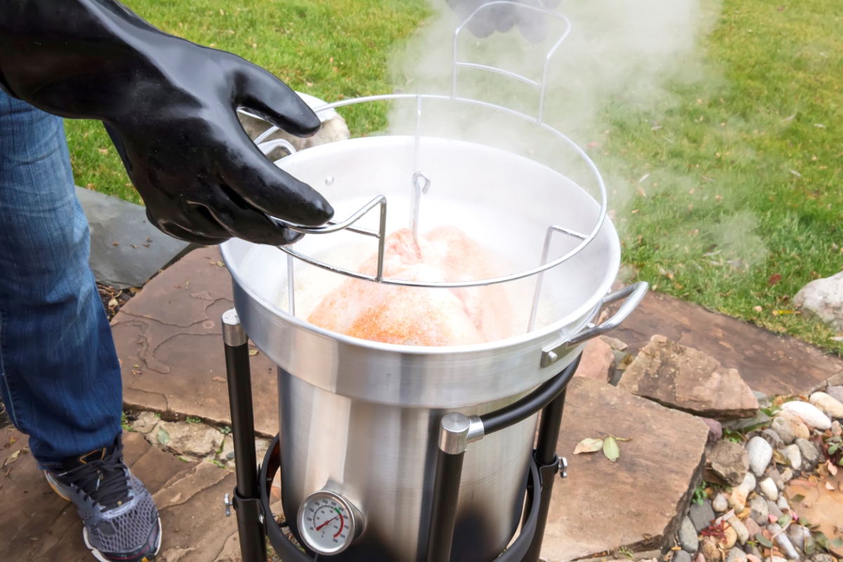 how to deep fry a turkey - gloved hand taking out turkey