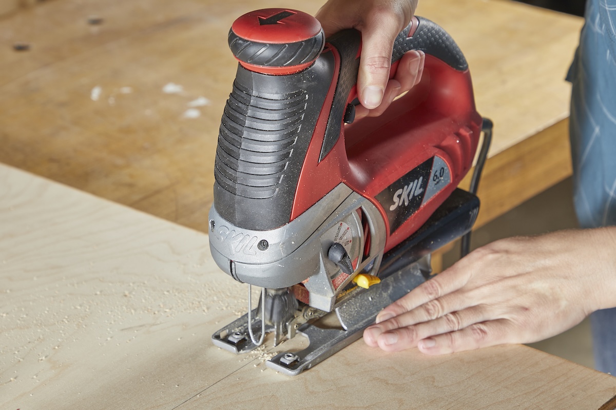 Jigsaw cutting through a piece of plywood.