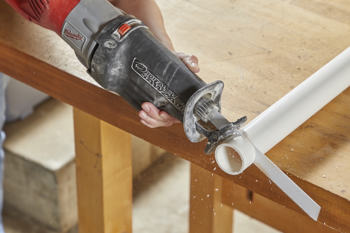 Reciprocating saw cuts through a piece of PVC pipe.