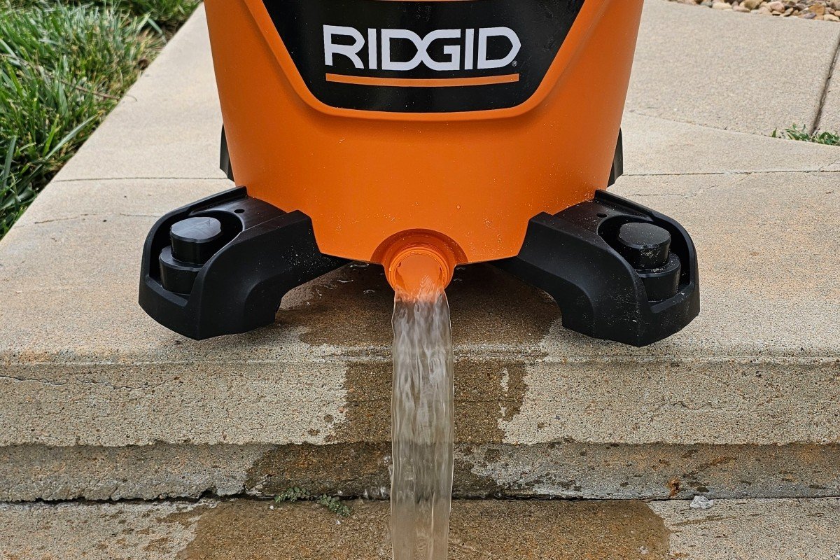 A close up view of an orange shop vac draining water.