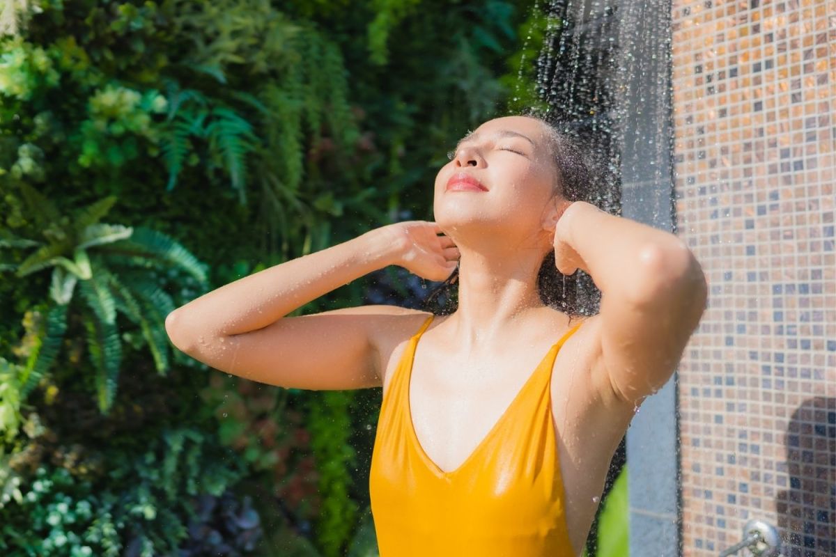A woman in a yellow bathing suit using the best outdoor shower option