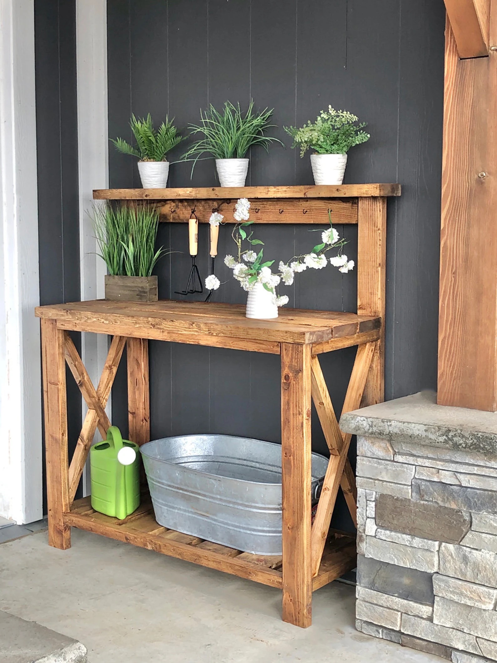 Farmhouse-style potting bench with potted plants on top shelf