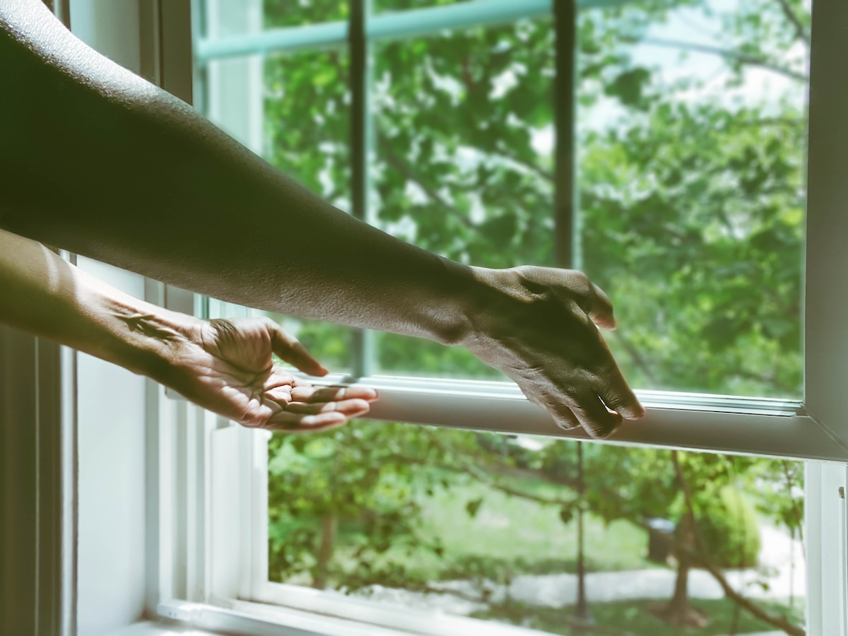 Close-up of woman's hands opening window.