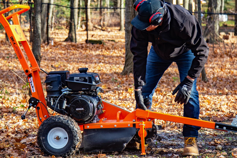 A person adjusting the best stump grinder option while in a wooded area