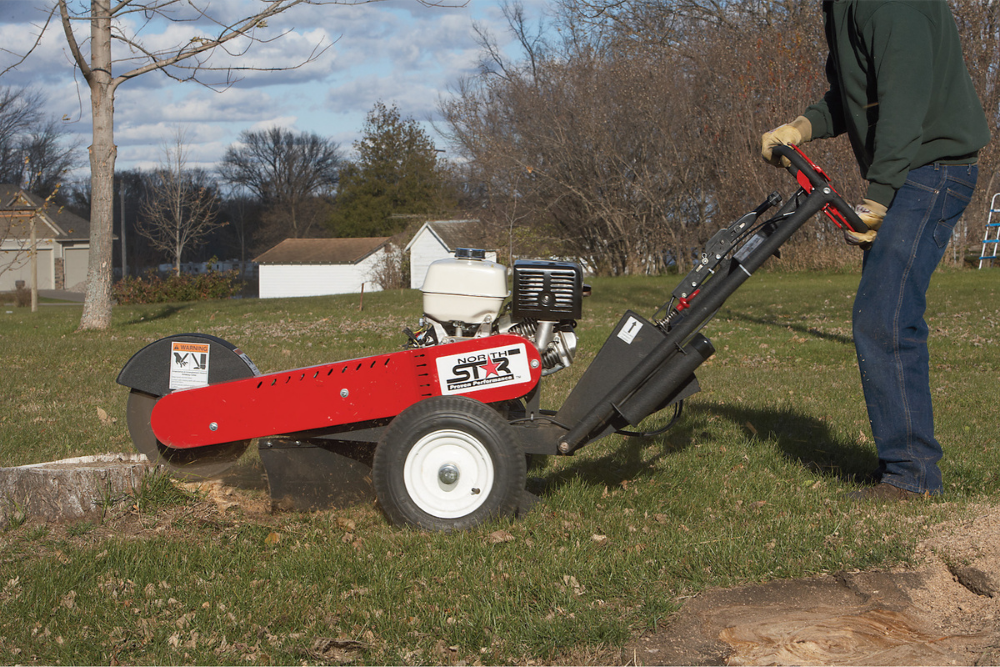 A person using the best stump grinder option in a ranch yard