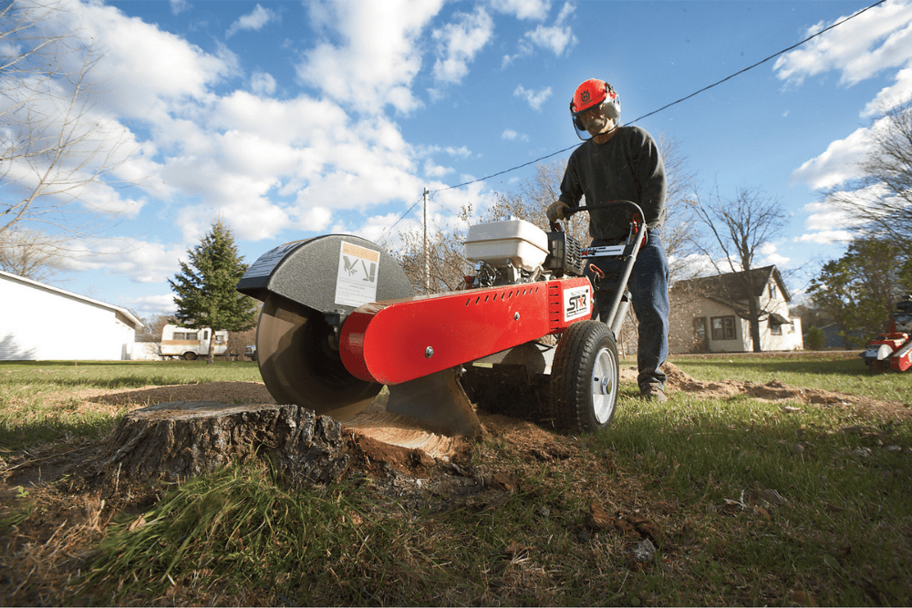 A person using the best stump grinder option to work on removing a stump