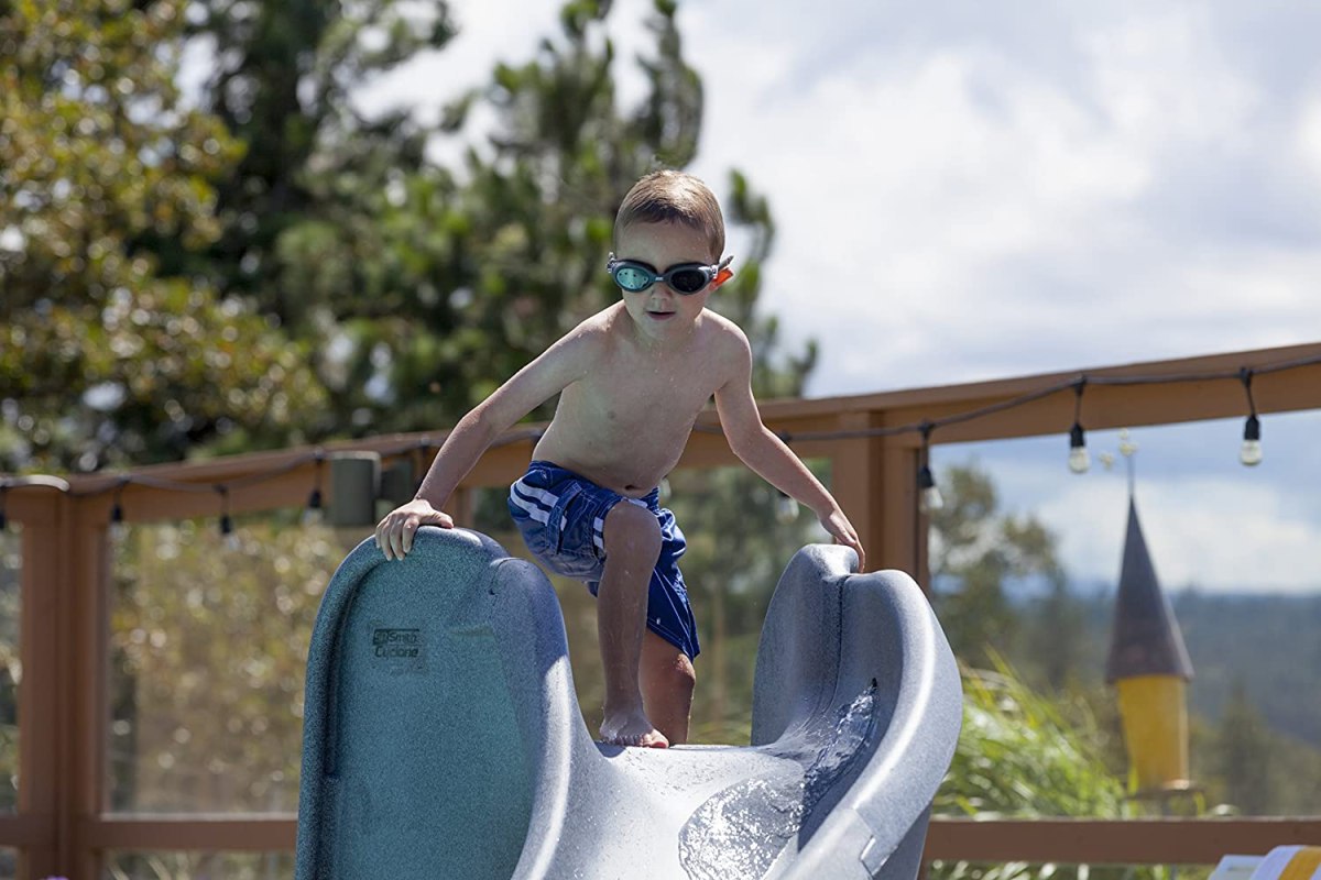 A child at the top of the best inground pool slide option preparing to slide down