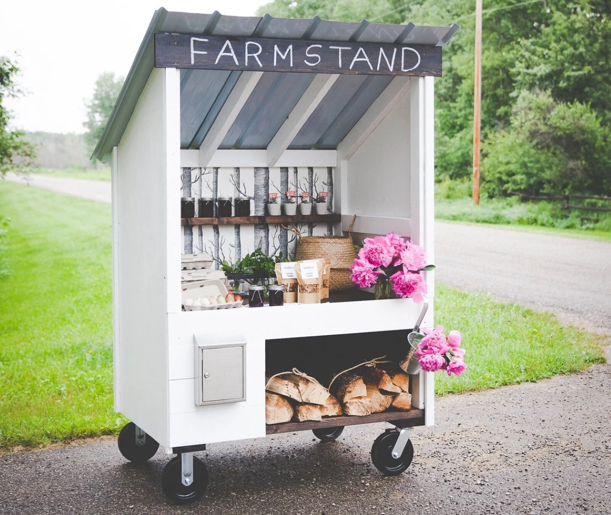 White wooden farm stand on wheels.