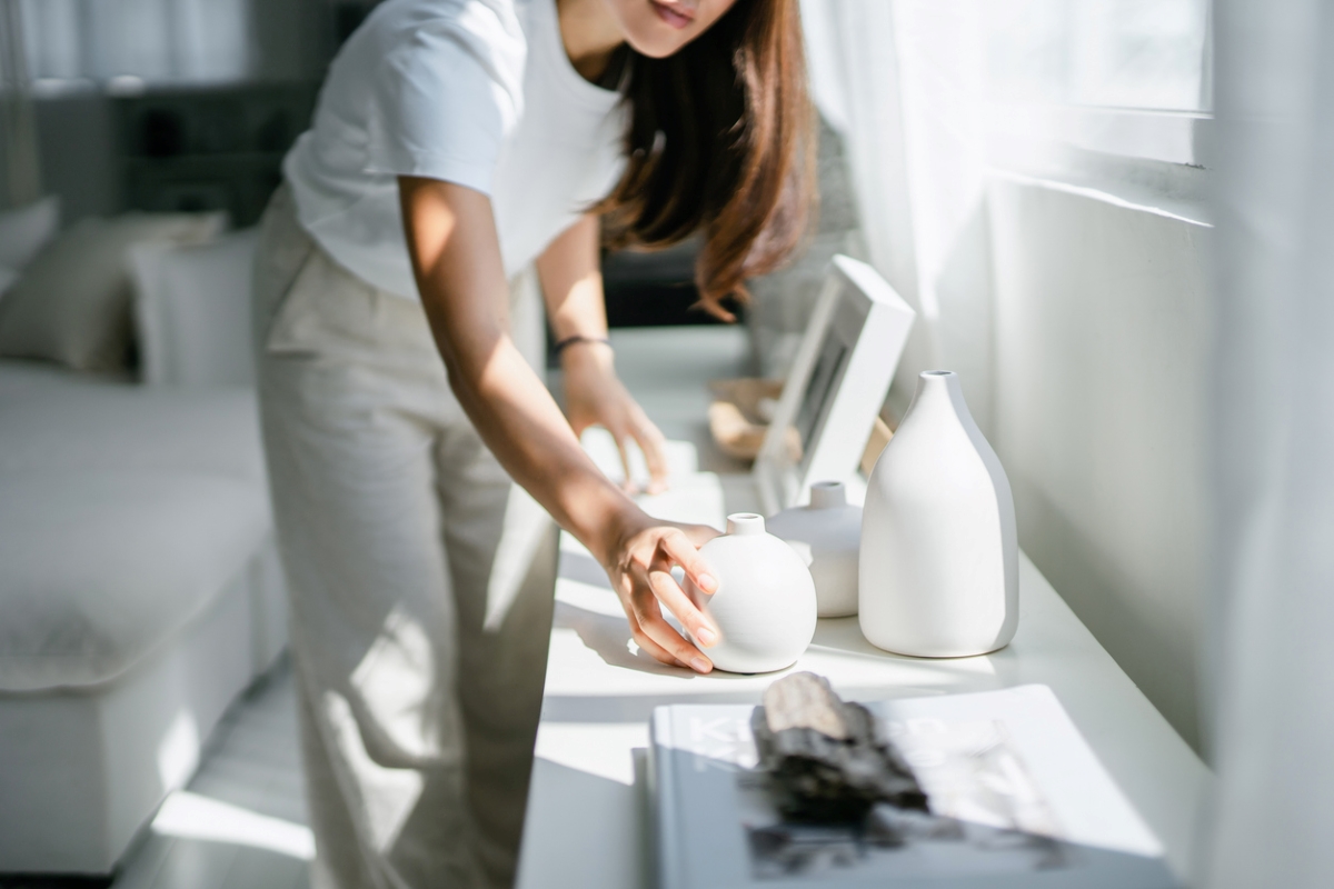 Woman placing white ceramic on table.