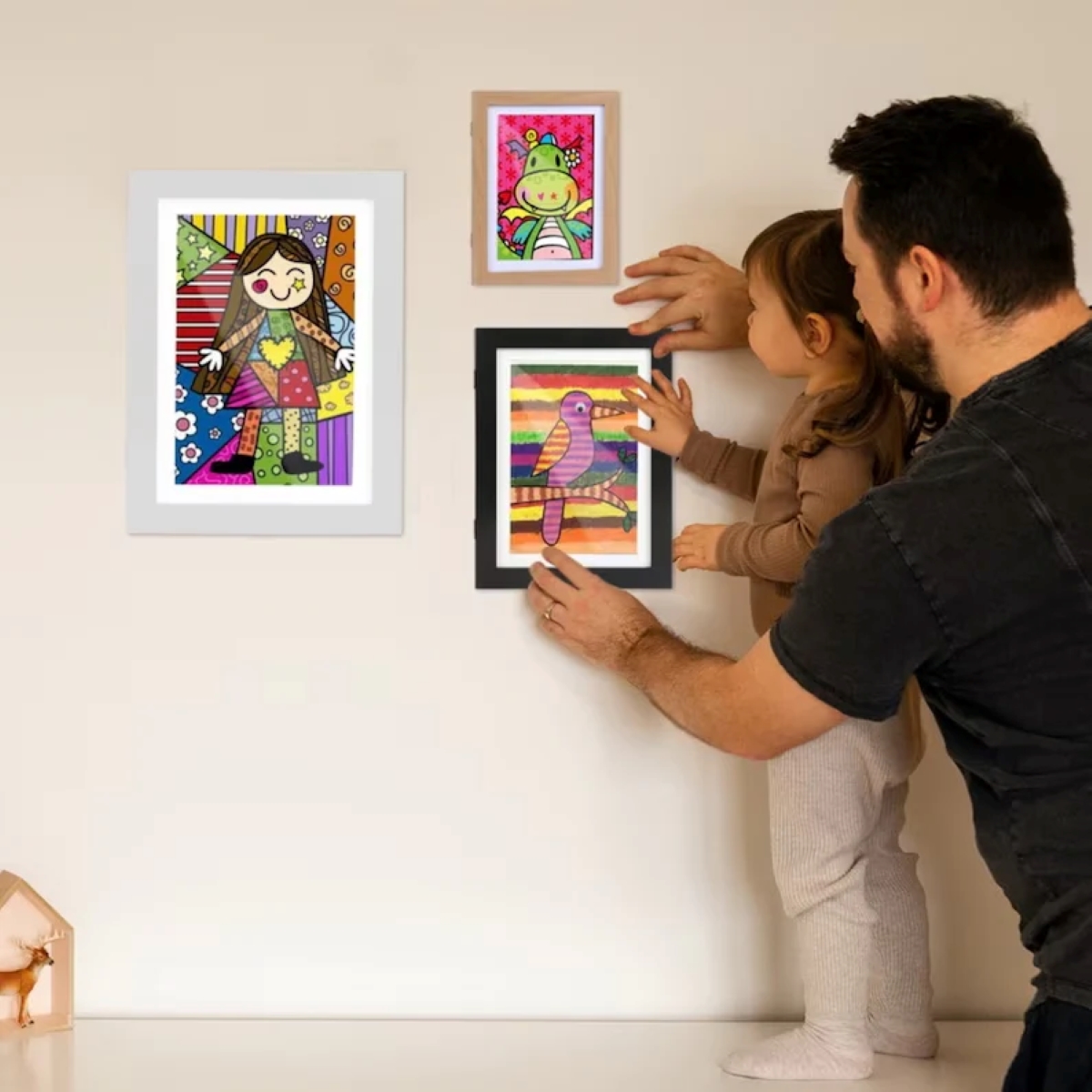 Parent and child inserting art in frame.