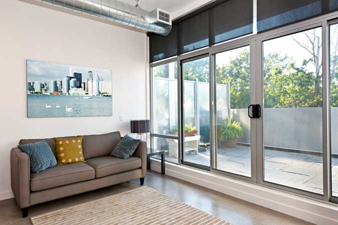 Sliding glass doors installed in a living room with a couch inside and a view of a small outdoor area.