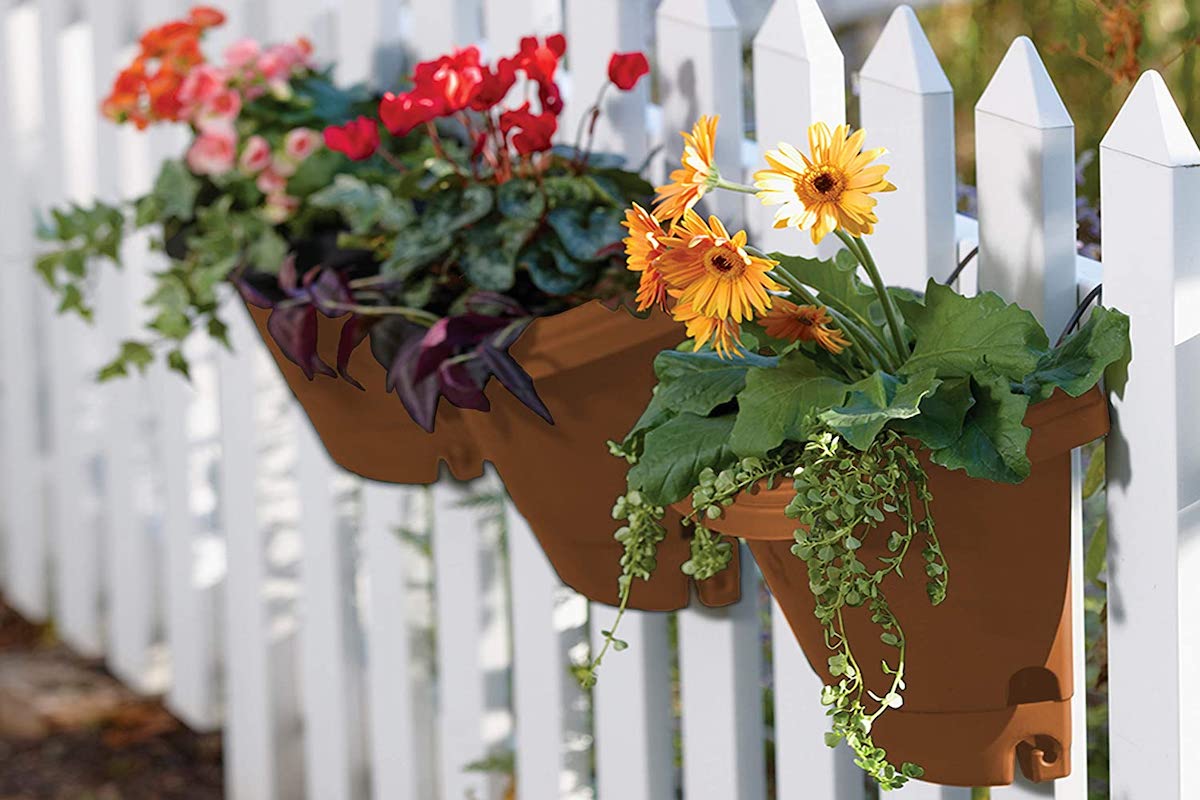 Flower baskets hanging on a white picket fence.