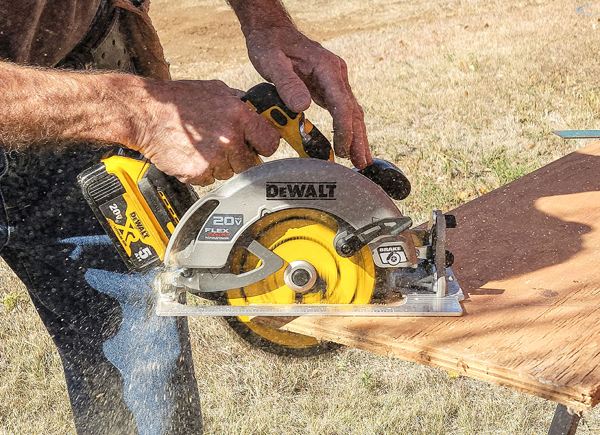A builder using a DeWalt circular saw to cut a sheet of plywood.
