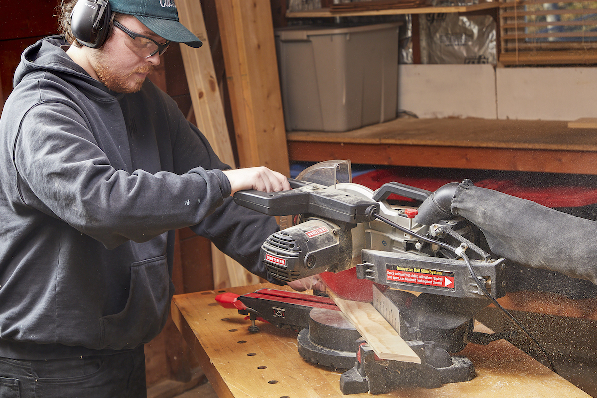 Man using a miter saw in a workshop.