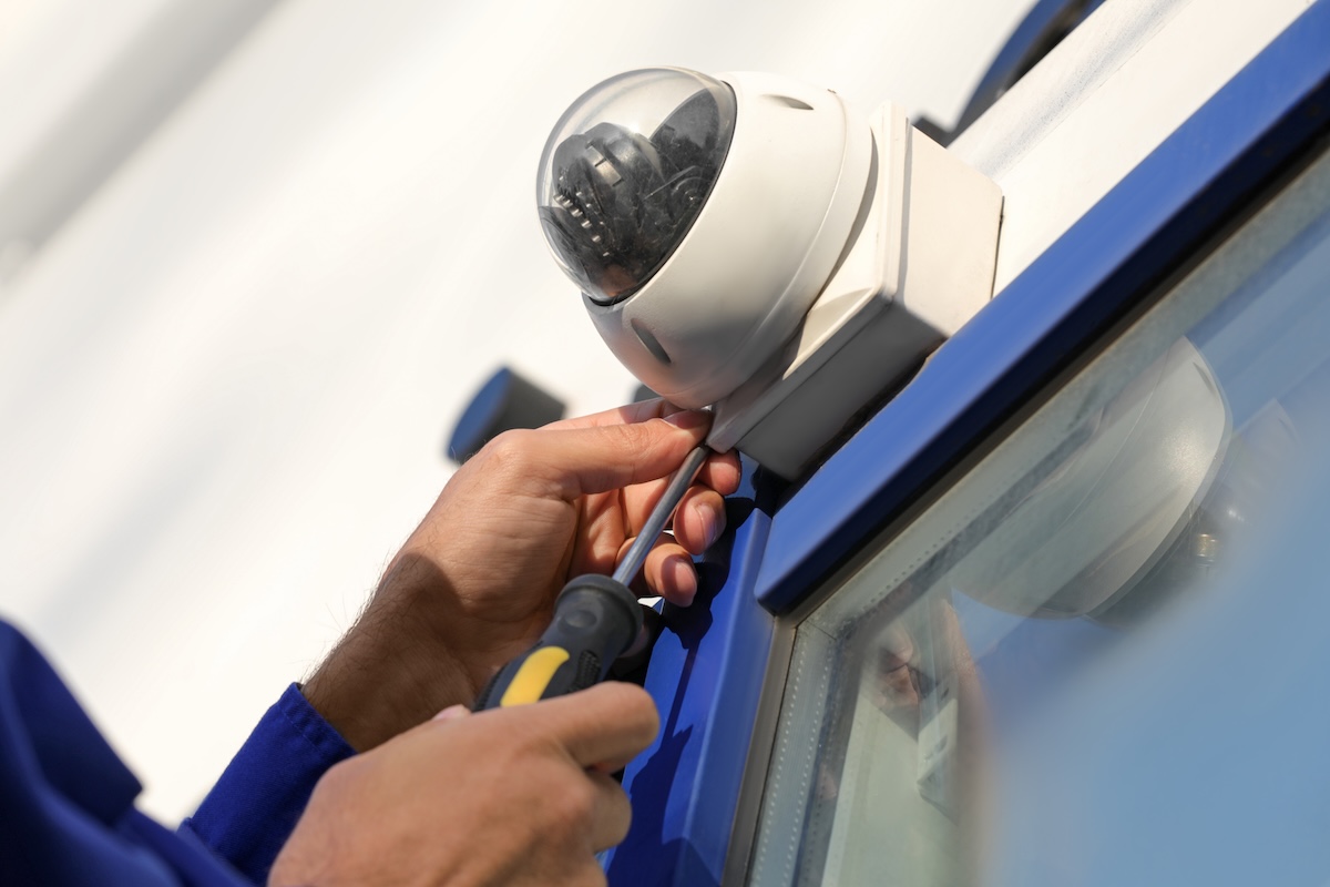 A technician installs a home security camera above a glass door.