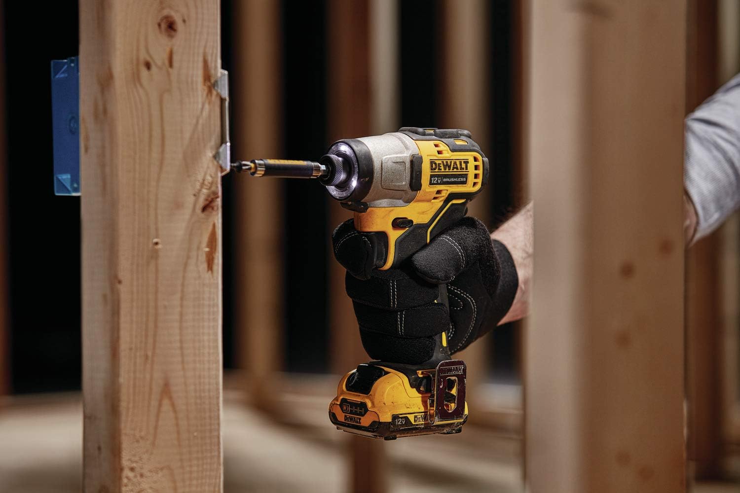 A person using the best DeWalt impact driver to install an electric box on wooden framing.