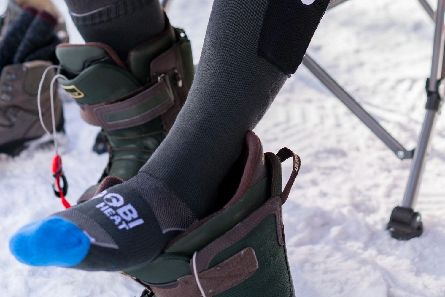 A person taking their foot out of a ski boot in a snowy setting while wearing Gobi heat tread heated socks.