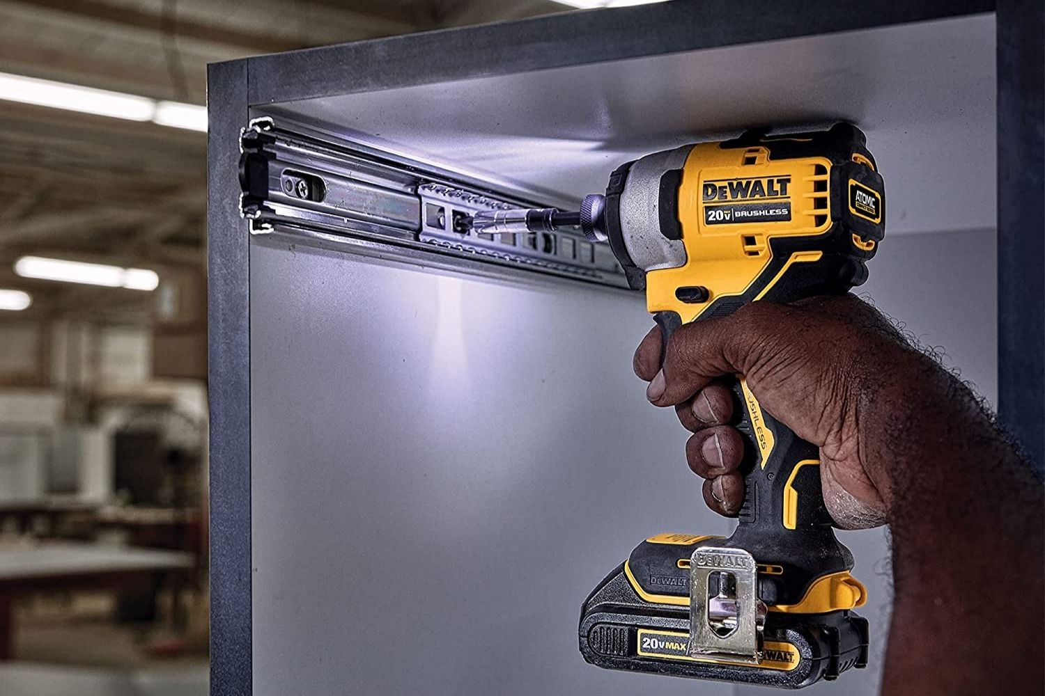 A person using the best DeWalt impact driver to install drawer tracks in a cabinet.