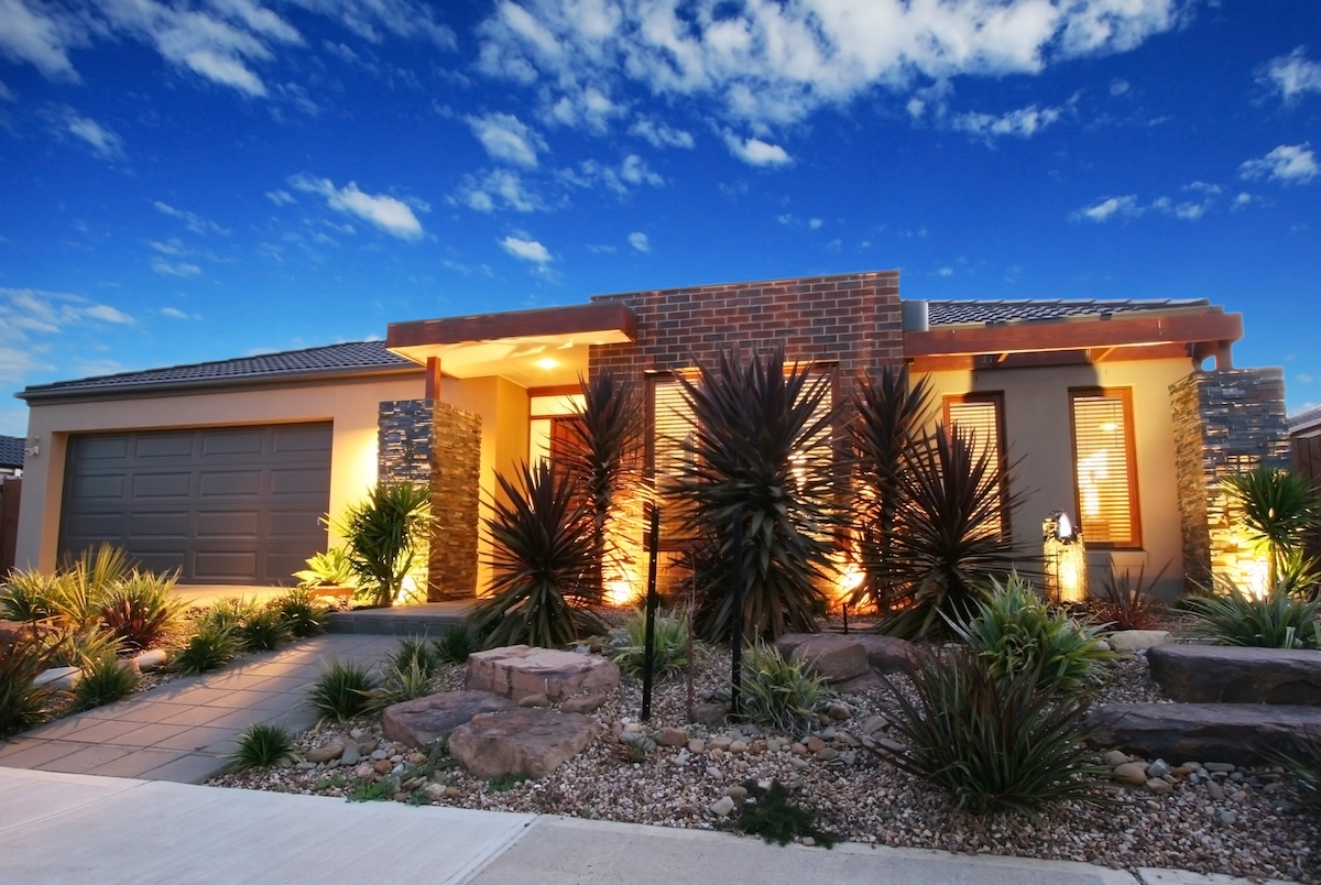 Dusk shot of a contemporary home illuminated by lights under the porch and deck area.