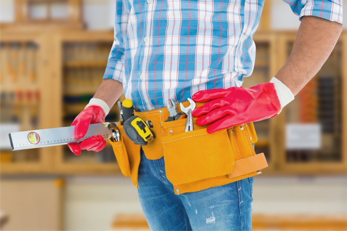 man wearing tool belt full of tools, and red work gloves