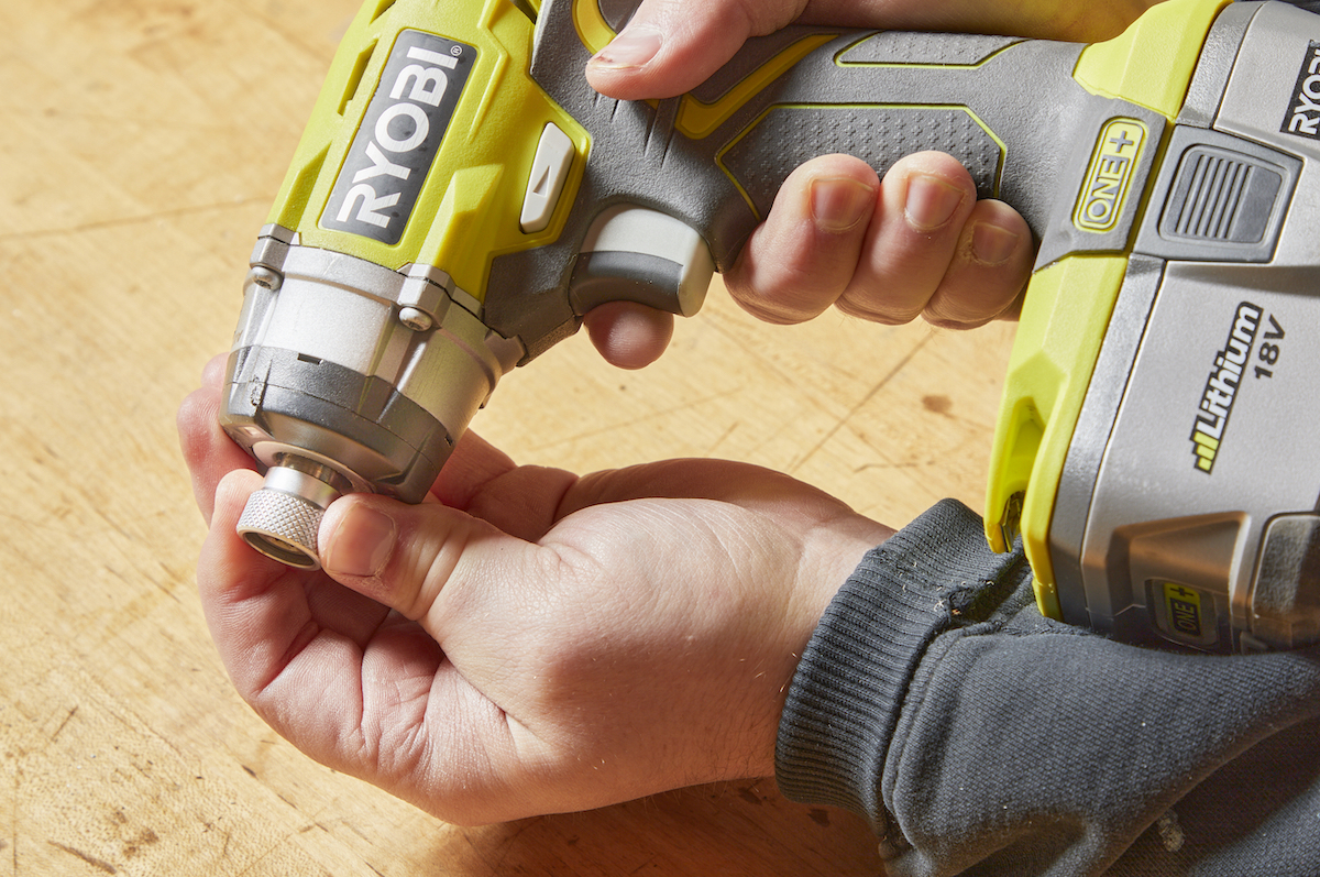 Handyperson grips base of the chuck on an impact driver.