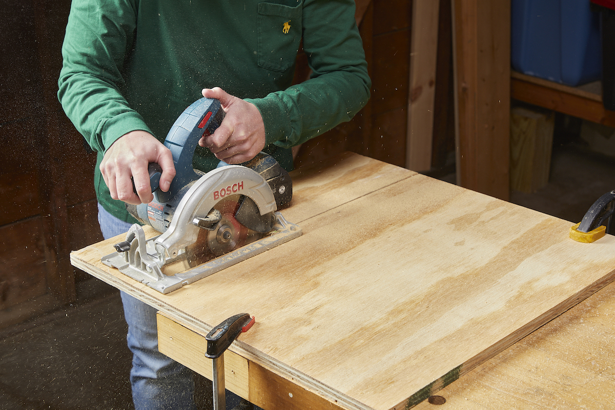 Woman finishes cutting a plywood board with a circular saw.